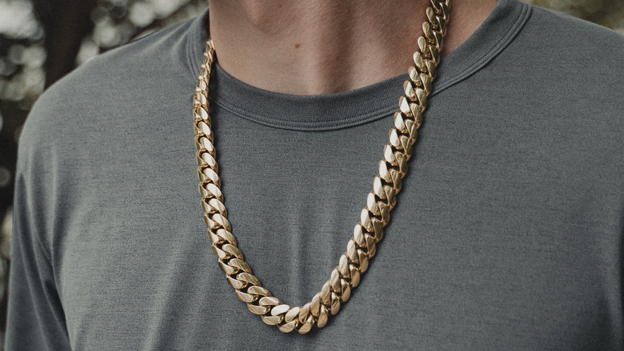 Man wearing a thick handmade solid gold Miami Cuban link chain over a grey t-shirt — genuine 10kt and 14kt gold Cuban link chains from Liry's Jewelry