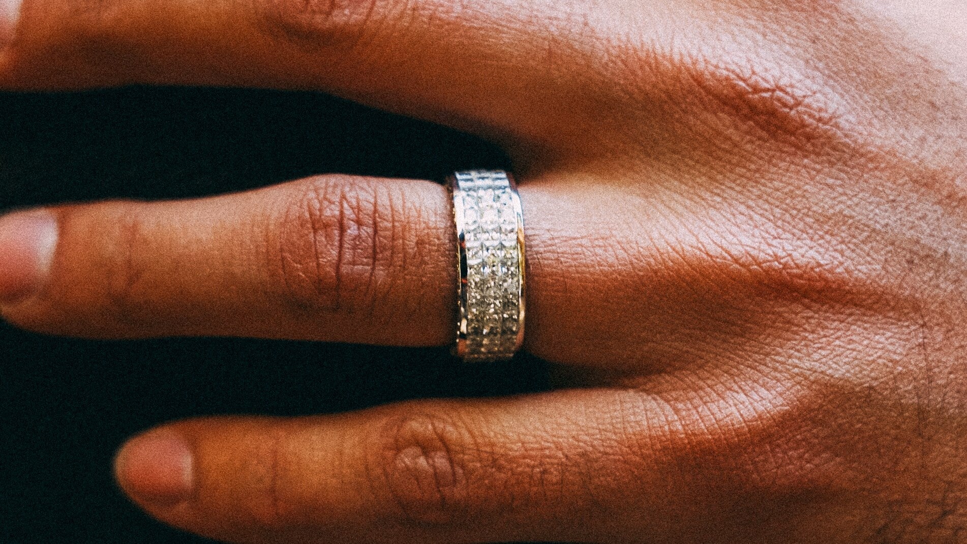 Man wearing a wide iced-out diamond wedding band in solid gold — men's wedding bands made to order from Liry's Jewelry