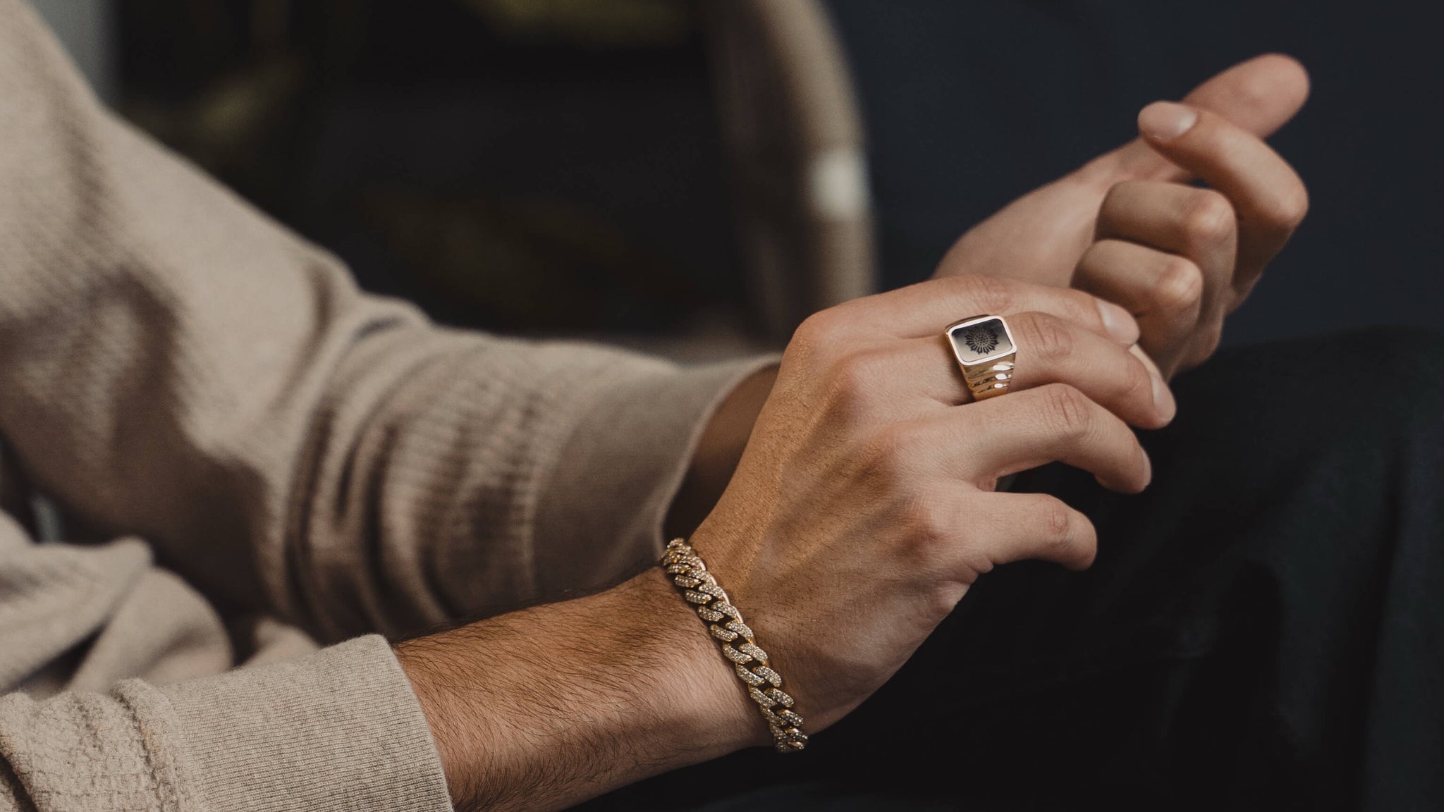 Man wearing a solid gold signet ring and diamond Cuban Link bracelet from Liry's Jewelry