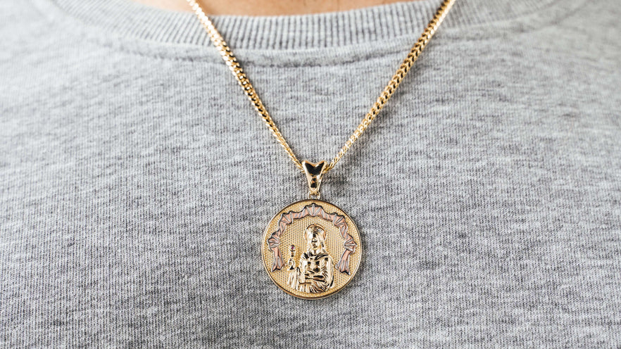 Solid gold Saint Barbara medallion pendant on a gold miami cuban link chain worn over a grey sweatshirt — religious gold pendants and charms from Liry's Jewelry