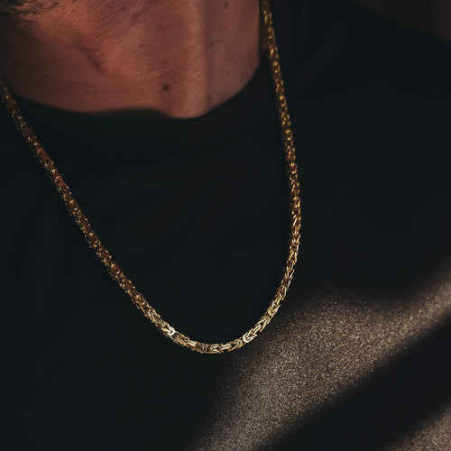 close up image of a gold byzantine chain on a black t shirt
